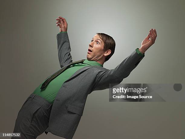 mid adult businessman falling backwards, portrait - man shock stockfoto's en -beelden