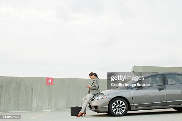 businesswoman texting on mobile phone in car park - remains stock pictures, royalty-free photos & images