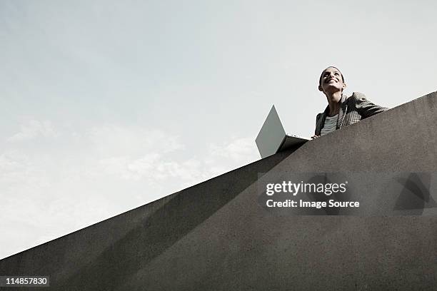 businesswoman leaning over wall with laptop, low angle - car park barrier stock pictures, royalty-free photos & images