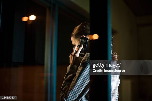 businesswoman using mobile phone in office at night - mystery stock pictures, royalty-free photos & images