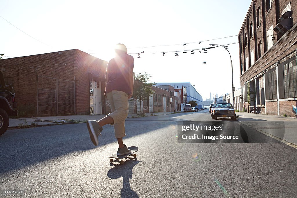 Skateboarder on urban street in sunlight