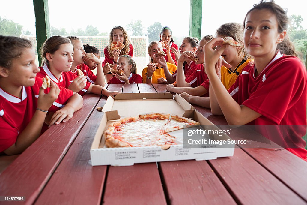 Female soccer team having pizza