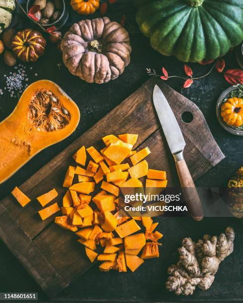 diced ​​pumpkin on cutting board with knife - squash seeds stock-fotos und bilder