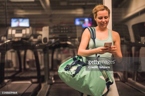 woman using mobile phone at gym entrance. - entering gym stock pictures, royalty-free photos & images