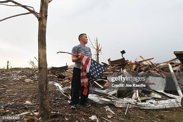 Kerry Roberts prepares to fold an American flag before a driving rain storm swept through the area as he and other volunteers searched for items to...