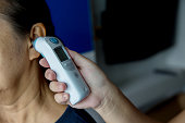 Doctor checking patient's temperature in the ear with Tympanic Thermometer, inside the hospital or clinic.