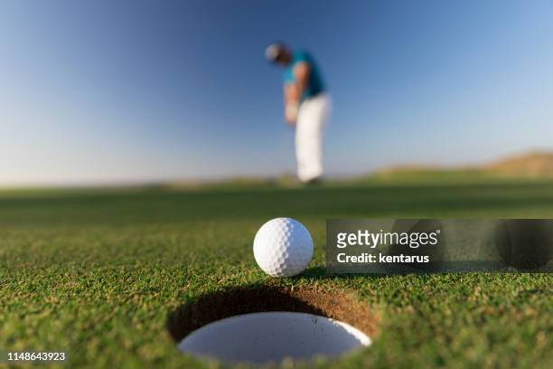 esfera de golfe que entra no furo após o curso bem sucedido-feche acima-golf das ligações - putt - fotografias e filmes do acervo