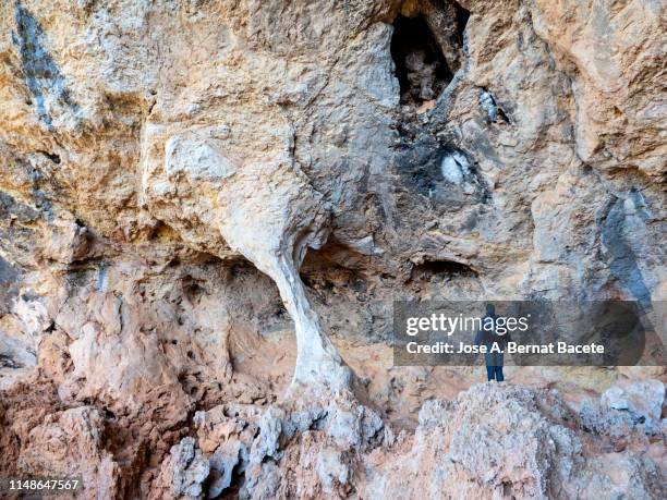 person inside a cave with rock formations eroded by wind and water in the nature reserve of the saw mariola. - rock face stock pictures, royalty-free photos & images