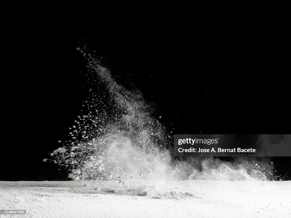 Explosion by an impact of a cloud of particles of powder and smoke of color white on a black background.