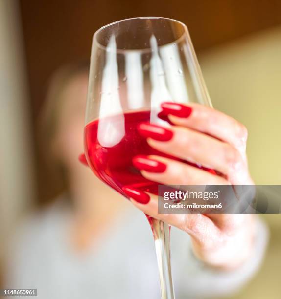 woman's hand holding glass of red wine. alcohol addiction - wine glass finger food stock-fotos und bilder