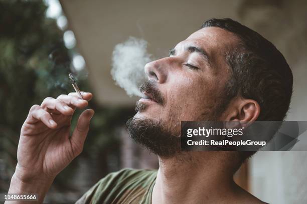 bearded man smoking a marijuana joint - smoking issues stock pictures, royalty-free photos & images