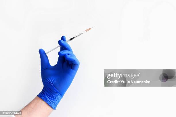 doctor's hand in blue medical glove holding syringe with medical solution isolated white background. flu vaccine concept - rubber gloves stockfoto's en -beelden