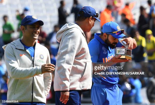 Indian cricket captain Virat Kohli is watched by India's Mahendra Singh Dhoni and India's head coach Ravi Shastri as he smells a box with Indian soil...