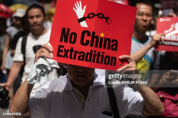 Protester marches with a placard during a rally against a controversial extradition law proposal in Hong Kong on June 9, 2019. - Huge protest crowds...