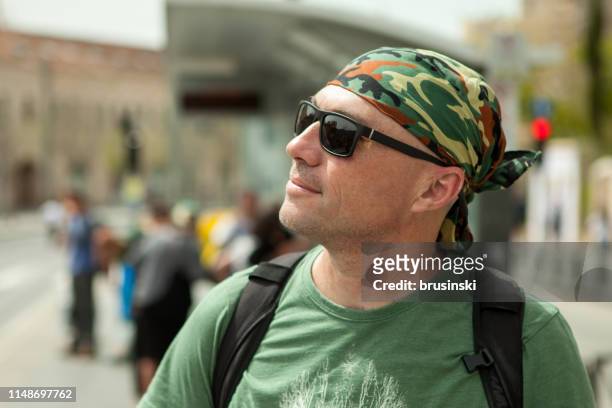 nahaufführung eines attraktiven 50-jährigen männlichen touristen in einem grünen t-shirt und bandana - 40 year old male face stock-fotos und bilder
