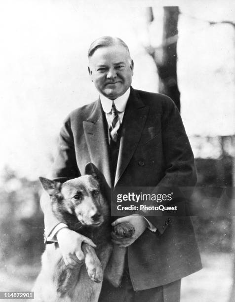 Portrait of American President Herbert Hoover as he poses with his pet dog King Tut, 1930s.