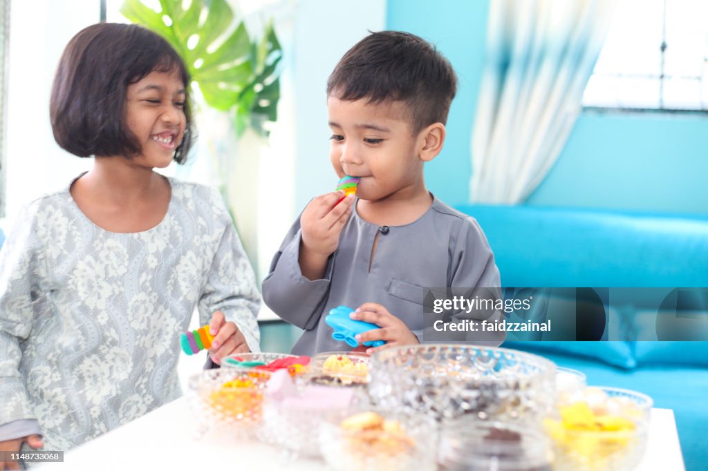 Two Children Eating Kuih on Hari Raya Aidilfitri