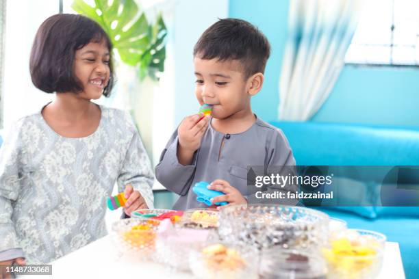 Two Children Eating Kuih On Hari Raya Aidilfitri High-Res Stock Photo