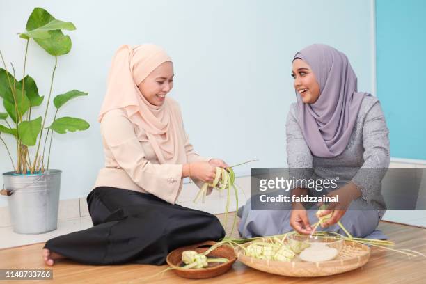 two malay muslim woman weaving ketupat for hari raya aidilfitri/ eid-ul-fitr - ketupat stock pictures, royalty-free photos & images