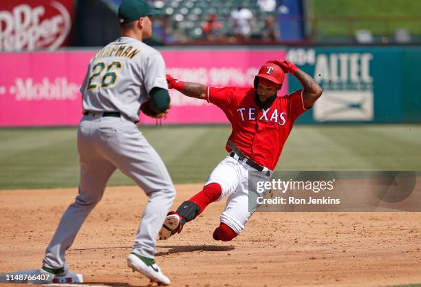 Danny Santana of the Texas Rangers slides into third base ahead of the throw to Matt Chapman of the Oakland Athletics on a triple in the third inning...