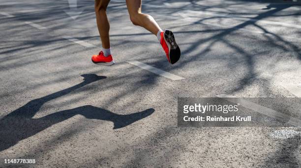 low section of athlete running on road in city - marathon stock-fotos und bilder