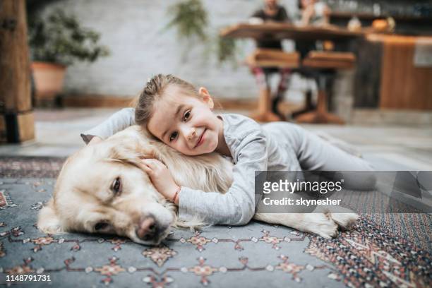 lächelnde mädchen und ihr goldener retriever auf teppich zu hause. - cute animals cuddling stock-fotos und bilder