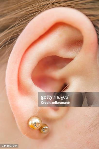 close up of a woman's ear and earring. - ear close up women stock-fotos und bilder