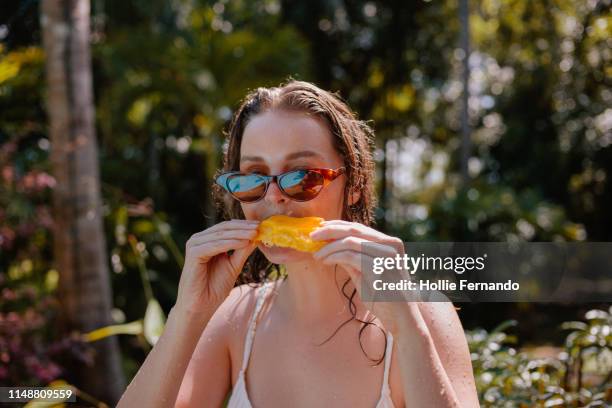 young woman eating mango on vacation - color food imagens e fotografias de stock