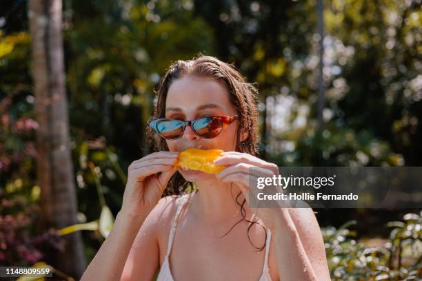 young woman eating mango on vacation - mango 個照片及圖片檔