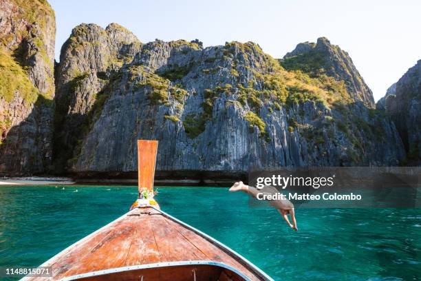 man diving from boat prow, phi phi island, thailand - long tail boat stock-fotos und bilder