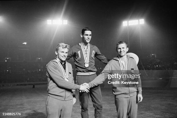 Gold medallist Fred Hansen of the United States stands on the podium with silver medallist Wolfgang Reinhardt and bronze medallist Klaus Lehnertz of...