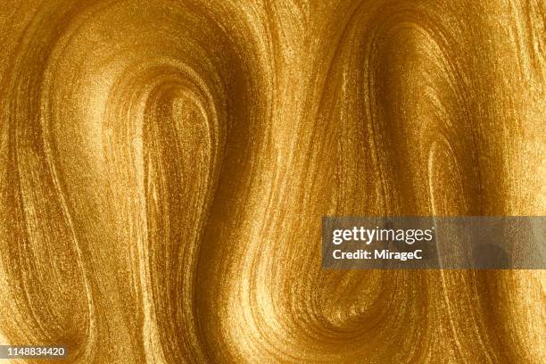 glittering golden paint wave pattern - gold paint stock pictures, royalty-free photos & images