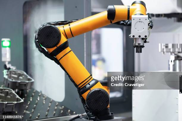 robot arm 's going to pick parts to cnc machine in the manufacturing factory. - robot stock pictures, royalty-free photos & images