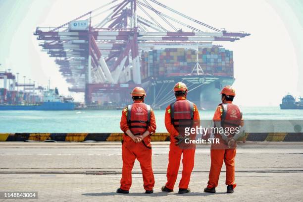 Staff members stand at a port in Qingdao, in China's eastern Shandong province on June 10, 2019. - China's exports beat gloomy forecasts to rebound...
