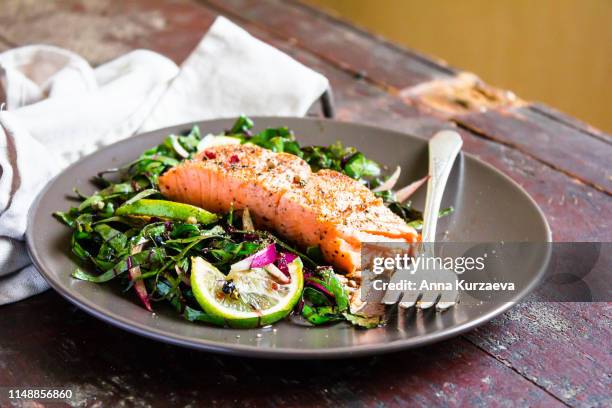 plate of salmon fillet steak roasted with spices served with fresh salad with lime fruit and peppercorns on a wooden table, selective focus. picnic fool. healthy and organic food concept. easter food. - lachs stock-fotos und bilder