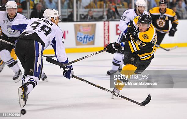 Brad Marchand of the Boston Bruins shoots the puck against Mike Lundin of the Tampa Bay Lightning in Game Seven of the Eastern Conference Finals...