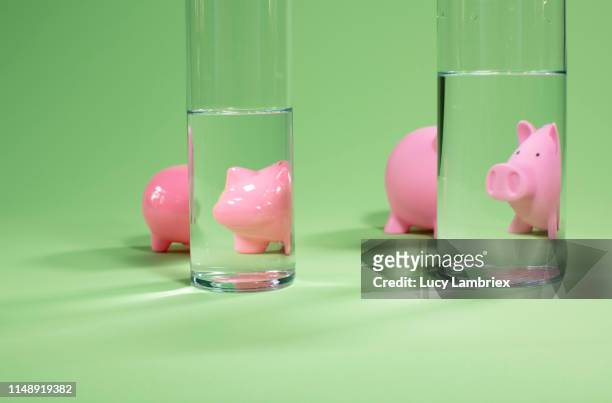 confusion: two piggy banks distorted by the breaking of light in water - glass figurine stock pictures, royalty-free photos & images