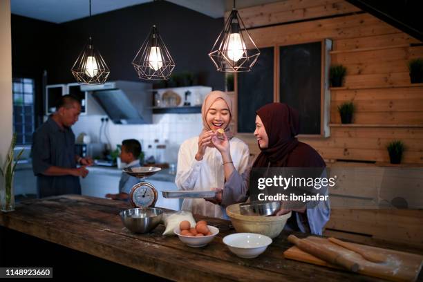mother and daughter baking in kitchen - ramadan ketupat stock pictures, royalty-free photos & images