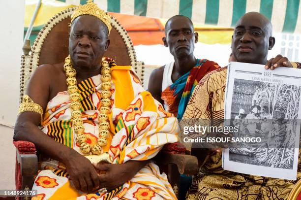 Man presents a copy of a page of a newspaper reading "1885, The division of Africa", as King Amon N'Douffou V , King of Krindjabo, capital of the...