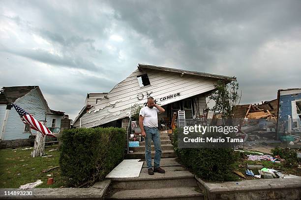 Stephen Dickson stands in front of his parent's home while on the lookout for looters at dusk five days after a massive tornado passed through the...