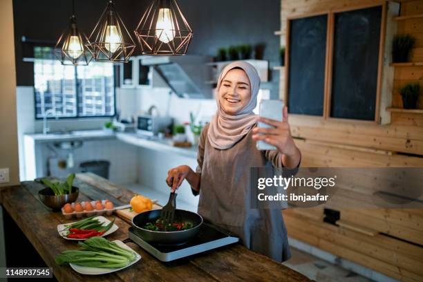 uma mulher que olha o telefone ao cozinhar - beautiful ramadan - fotografias e filmes do acervo