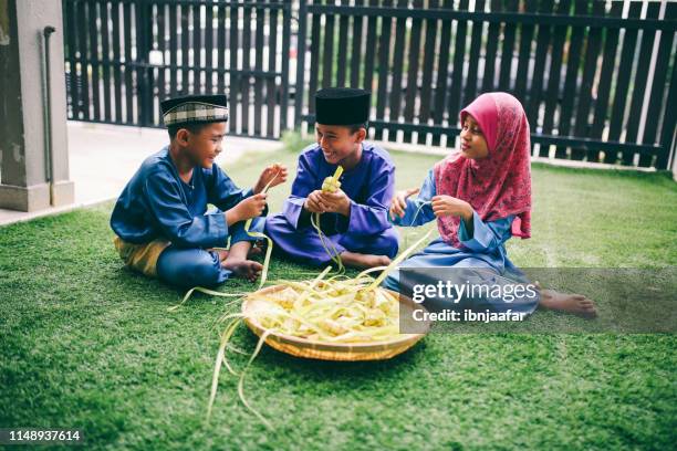 siblings preparing food in front of house - ketupat stock pictures, royalty-free photos & images