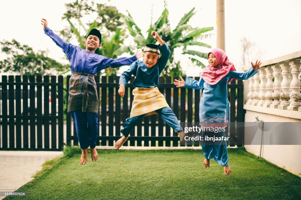 Three sibling playing in front of house