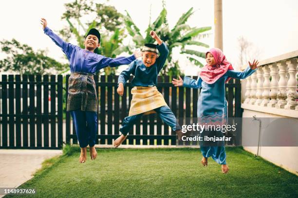 three sibling playing in front of house - ramadan eid stock pictures, royalty-free photos & images