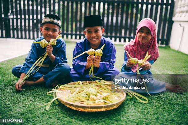 siblings preparing food in front of house - ketupat stock pictures, royalty-free photos & images