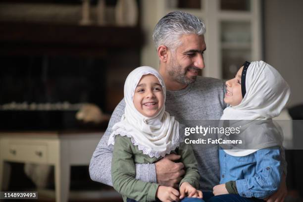 een jonge moslim meisje genieten van knuffeltijd met haar vader en zus - young muslim man stockfoto's en -beelden