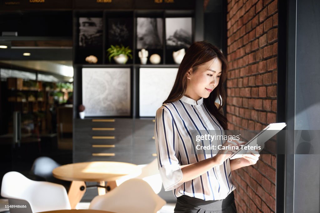 Elegant Chinese business woman using a tablet in an office