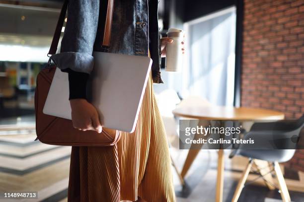 woman carrying laptop, purse and reusable coffee cup to work - coming home door stockfoto's en -beelden