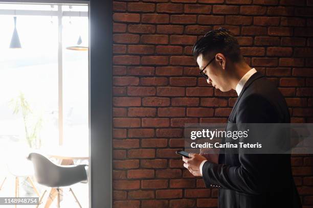 business man texting on a smart phone - taiwanese ethnicity stockfoto's en -beelden