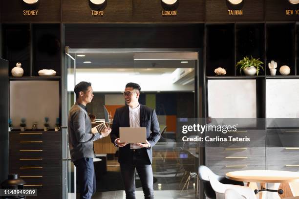 two handsome chinese men standing with laptops in an office - taipei business stock pictures, royalty-free photos & images